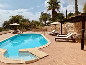 una piscina con sillas y sombrillas en un patio en Villa Botanica, en Silves