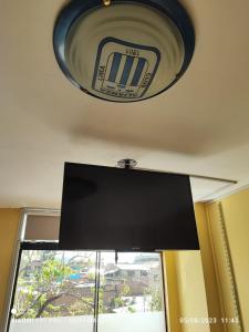 un reloj colgando del techo en una habitación con ventana en C&B APARTAMENTOS, en Jauja