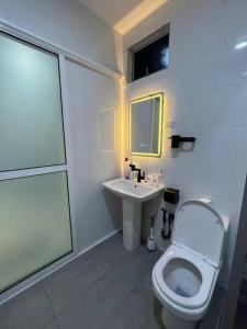 a white bathroom with a toilet and a sink at Homestay Tawau With Seaview. Anekayangan Homestay in Tawau