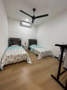 a room with two beds and a ceiling fan at Homestay Tawau With Seaview. Anekayangan Homestay in Tawau