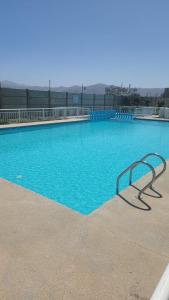 een groot blauw zwembad met een bankje erin bij I A pasos de la playa y del centro in La Serena
