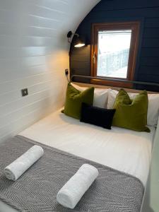 a bedroom with a bed with green and white pillows at Highland Stays - The Oaks Studio Pod in Fort William