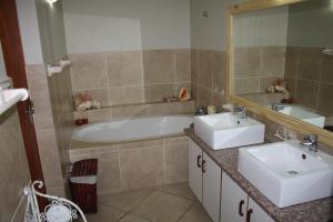 a bathroom with two sinks and a tub and a mirror at Beachcastle in Stilbaai