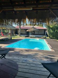 een groot blauw zwembad met een houten terras bij La Villa des Palmiers Bleus - Piscine & Jardin in Matoury