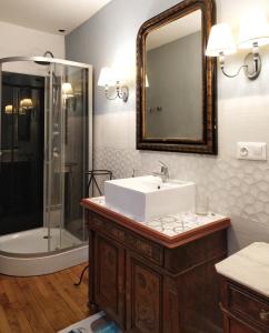 uma casa de banho com um lavatório e um chuveiro com um espelho. em La BOCQUILLONNE 