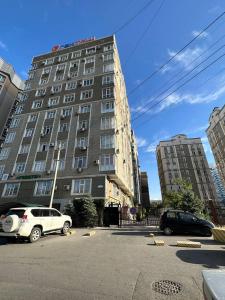 een groot gebouw met auto's geparkeerd op een parkeerplaats bij apartment on st. Frunze 553 in Bisjkek