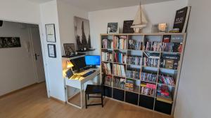 een kamer met een bureau en een boekenplank gevuld met boeken bij Paris'door Cozy 2P 50m² all equipped in a village in Pré Saint Gervais
