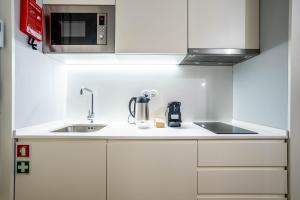 eine weiße Küche mit einer Spüle und einer Mikrowelle in der Unterkunft Sta Catarina 632 by LovelyStay in Porto