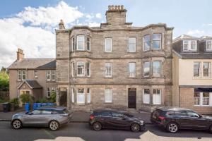 two cars parked in front of a large brick building at 44 Argyle Street - 2 Bed-1 Bath - Central in St. Andrews