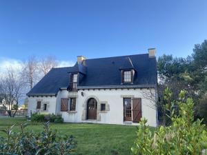 una casa blanca con techo negro y patio en 753 - Belle maison à Erquy à 1km5 des plages et 2km5 du centre, en Erquy