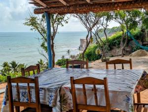 una mesa con sillas y vistas al océano en Chalé brilho do mar, en Icapuí