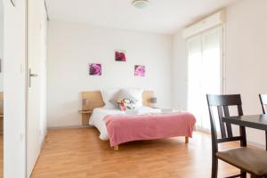 a bedroom with a bed with a pink blanket on it at Patio Parc Résidence in Argenton lʼÉglise