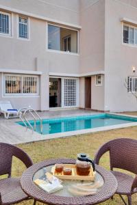 a table with a tray of food on it next to a swimming pool at ELIVAAS Shourya Bliss Lux 3BHK Villa with Pvt Pool, Udaipur in Udaipur