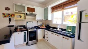 a kitchen with white cabinets and a black counter top at Descanse perto da praia in Porto Seguro