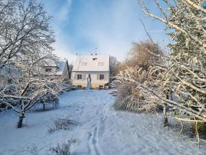 un cortile coperto da neve con una casa sullo sfondo di A la maison du bonheur a Neuilly-sous-Clermont