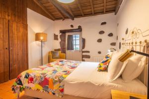 a bedroom with a bed with a colorful quilt at Aldeia da Cuada in Faja Grande