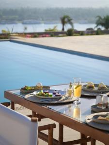 The Zen Wellness Resort في أسوان: طاولة مع أطباق من الطعام والمشروبات بجوار حمام سباحة