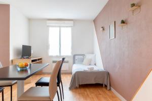 een klein appartement met een bed en een tafel en stoelen bij Patio Parc Résidence in Argenton lʼÉglise