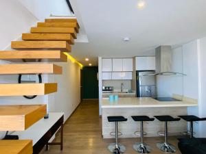 a kitchen with a staircase and a kitchen with stools at Hermoso dúplex nuevo con balcón y terraza in Cuenca