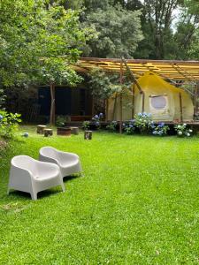 a yard with two white chairs and a tent at Wild Glamping Portugal with hot tub to relax in Viana do Castelo in Viana do Castelo