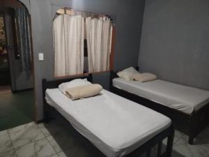two twin beds in a room with a window at Mi Casa Tica Backpackers in Monteverde Costa Rica