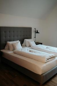 1 cama grande con sábanas y almohadas blancas en GUESTHOUSE RIEGERSBURG - Das Haus der guten Geister, en Riegersburg