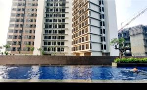 een persoon die zwemt in een zwembad voor een gebouw bij Apt Roseville Soho and suite studio w/ wifi & pool in Dadap