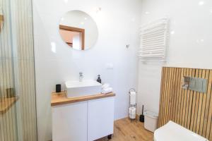een witte badkamer met een wastafel en een spiegel bij Wichrowe Wzgórze in Krajno Pierwsze