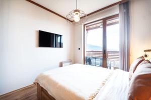 een slaapkamer met een bed, een tv en een raam bij Bansko Best View Apartment in Bansko