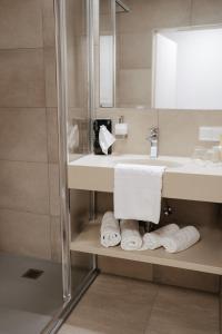 ein Badezimmer mit einem Waschbecken, einem Spiegel und Handtüchern in der Unterkunft GUESTHOUSE RIEGERSBURG - Das Haus der guten Geister in Riegersburg