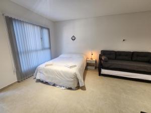 a white bedroom with a bed and a couch at PH Patagonia Carrera Aparts in Puerto Madryn