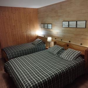 two beds in a room with wood paneling at Chalet La Bachole in Charancieu