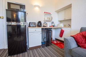 a small kitchen with a refrigerator and a counter at Cosy Flat in Victorian Villa- Parking & Garden in Torquay