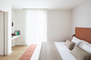 a bedroom with a bed with white walls and a window at Murmuri Residence Concepció in Barcelona