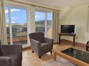 a living room with a couch chair and a television at Glen View Lodge in Inverness