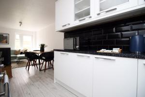 a kitchen with white cabinets and a black brick wall at 4 BR with FREE on street parking in Bristol