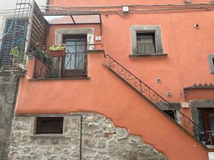 DOMUS TUSCIA APARTMENTS San Faustino guesthouse في فِتيربو: مبنى برتقالي مع درج وشرفة