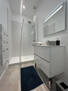 a white bathroom with a sink and a mirror at L'aristide in Épinal