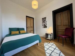 a bedroom with a bed and a chair and a door at L'aristide in Épinal