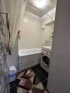 een badkamer met een bad en een wasmachine bij apartment on st. Frunze 553 in Bisjkek