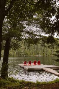 cuatro sillas rojas sentadas en un muelle en un lago en Waterfront private cottage on Koshlong Lake, en Haliburton