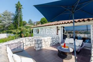 a patio with a blue umbrella and a stone wall at HSUD0085-Sansovino in Cannes