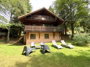 a group of chairs sitting in the grass in front of a house at LE GRIZZLY Chalet en bois avec SPA Jacuzzi in La Bresse