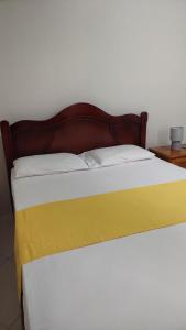 a bed with a wooden head board and white sheets at Stay A While in Saint Philip