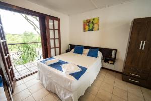 a bedroom with a bed with blue pillows and a balcony at Vacacional Dayman in Termas del Daymán