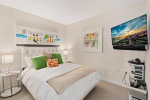 a white bedroom with a bed and a flat screen tv at Luxury Living at The Grand in Wildwood