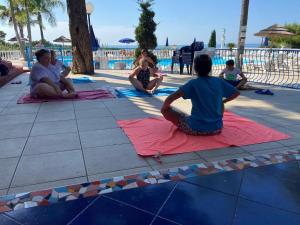 a group of people sitting on mats by a pool at Residence Emarine in Peschici