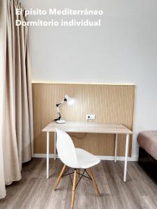 escritorio blanco con silla y lámpara en El pisito mediterráneo en Melilla