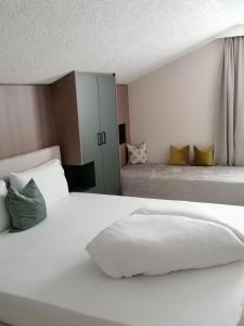 a white bedroom with two beds and a cabinet at Hotel Garni Tannleger B&B in Brand