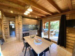 una cocina con mesa y sillas en una cabaña en L'OURSBLANC Chalet en rondins, en La Bresse